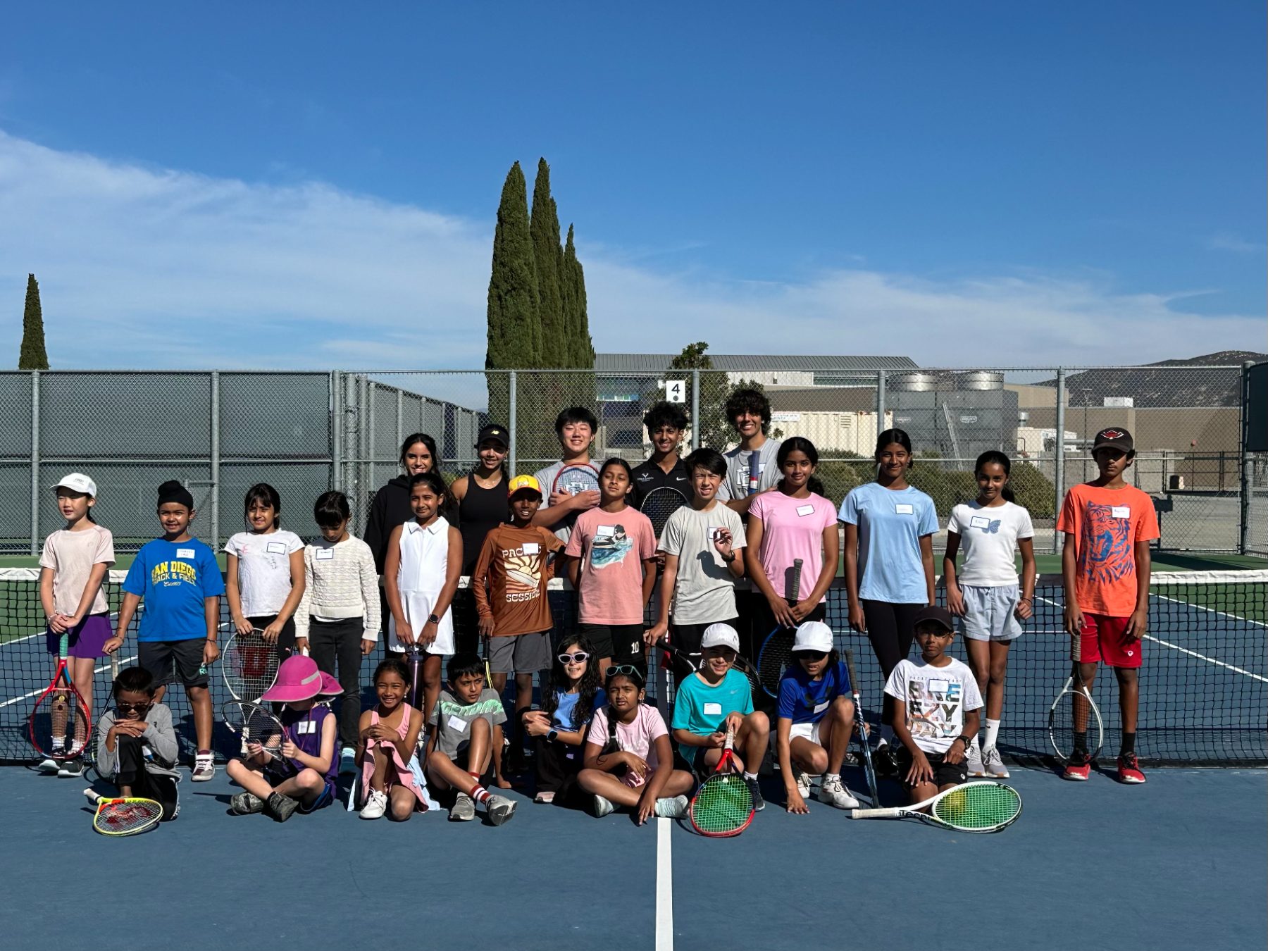 large group clinic, many kids and coaches on public courts